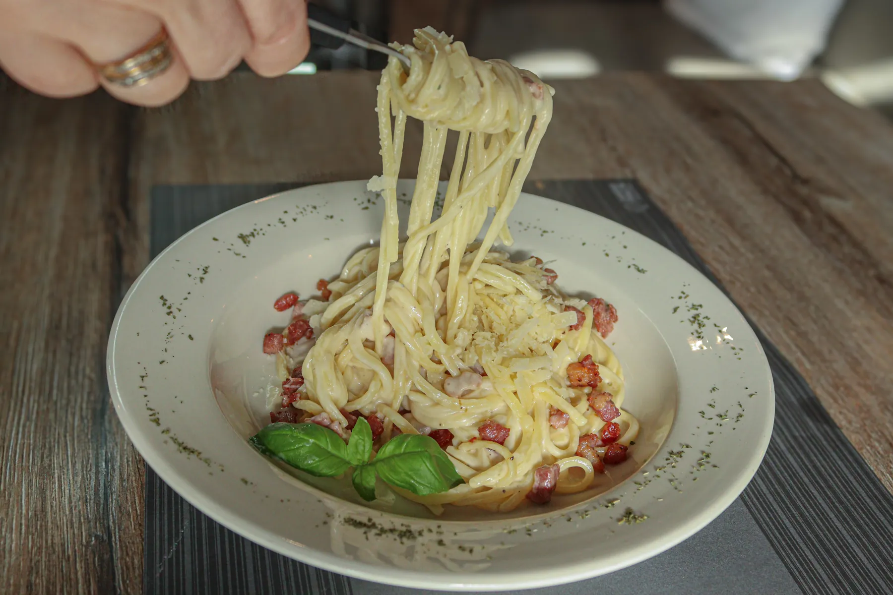 Pasta carbonara die met een vork uit het bord wordt opgedraaid