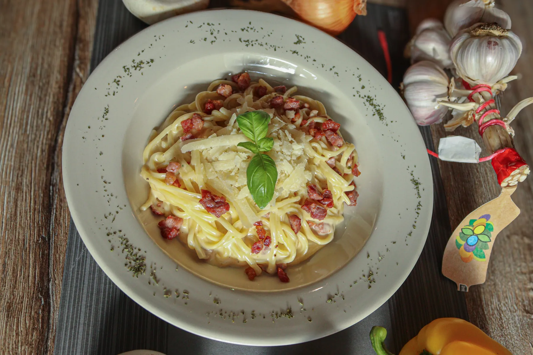 Pasta carbonara met room, spek en basilicum op een wit bord