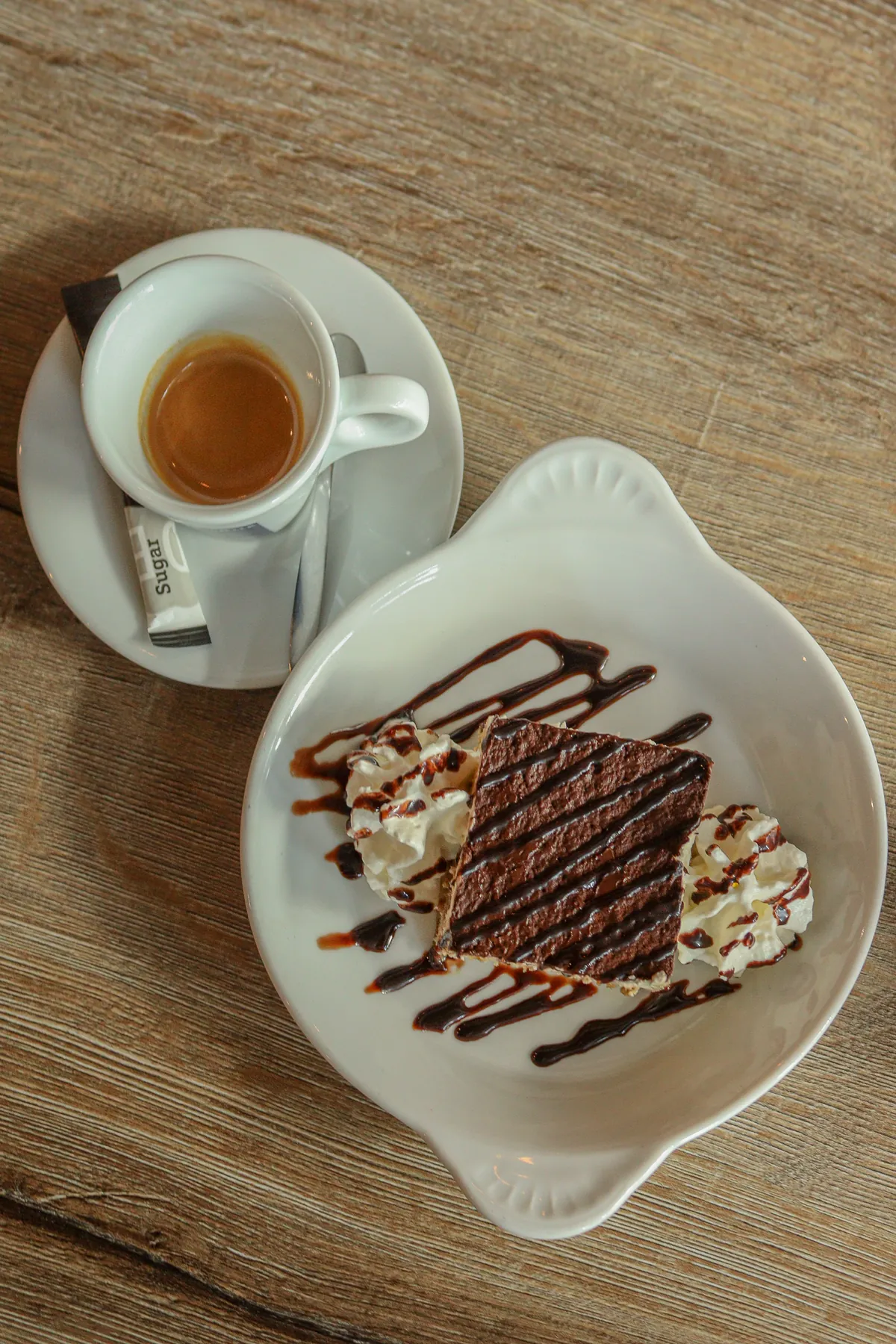 Huisgemaakte tiramisu met slagroom, naast een kopje espresso
