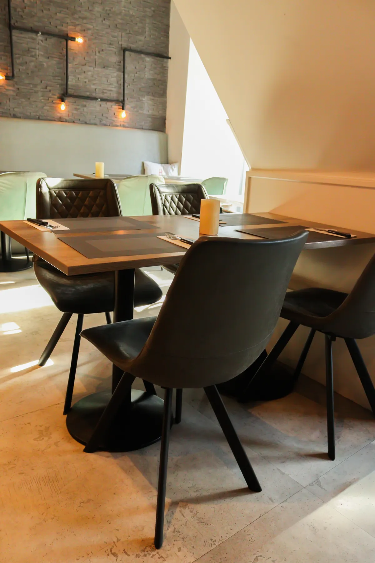 Een tafel met leren bank bij een hoog raam, met een kaars erop