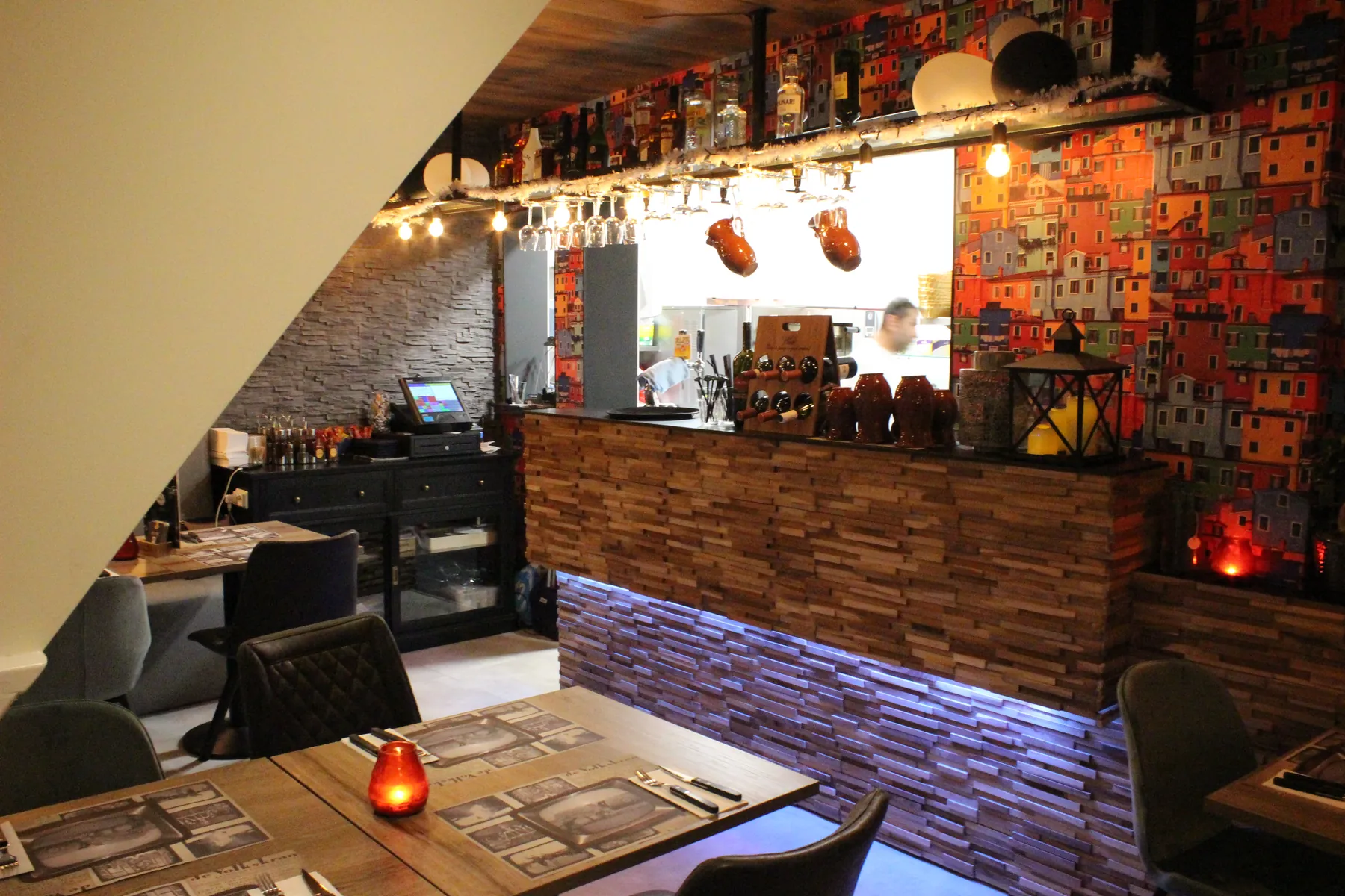 De bar met houten toog en flessen, gezien vanaf een tafel in de zaal