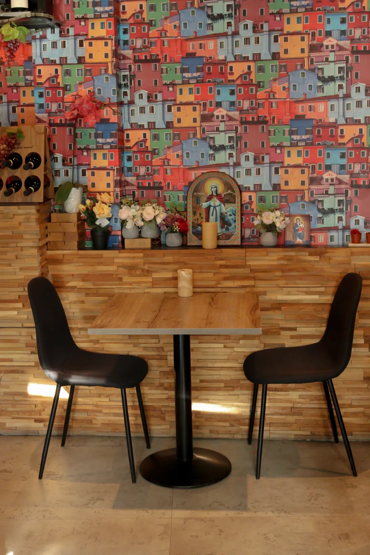 Het wandbehang met Italiaanse vissershuisjes achter een gedekte tafel met bloemen
