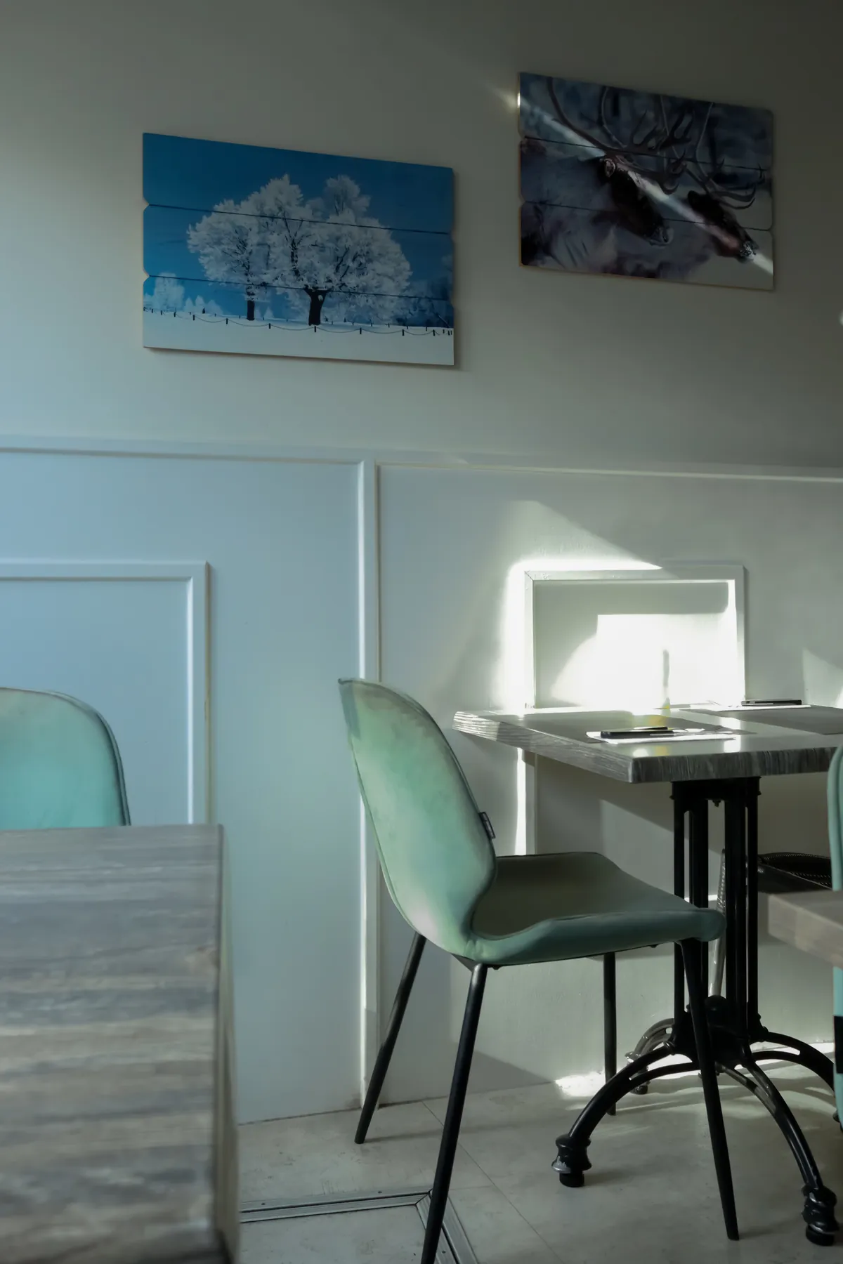 Een gedekte tafel voor twee bij een lichte wand met ingelijste foto's