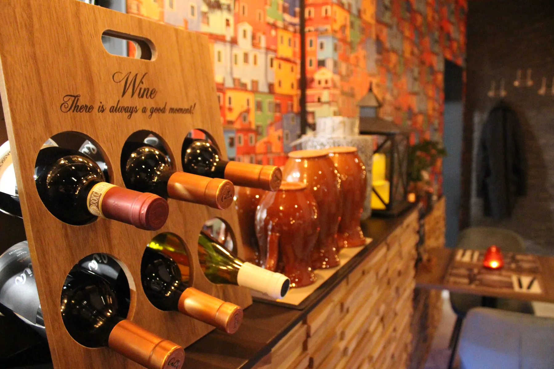 Een houten wijnrek met flessen, met de woorden Wine en There is always a good moment! erin gegraveerd