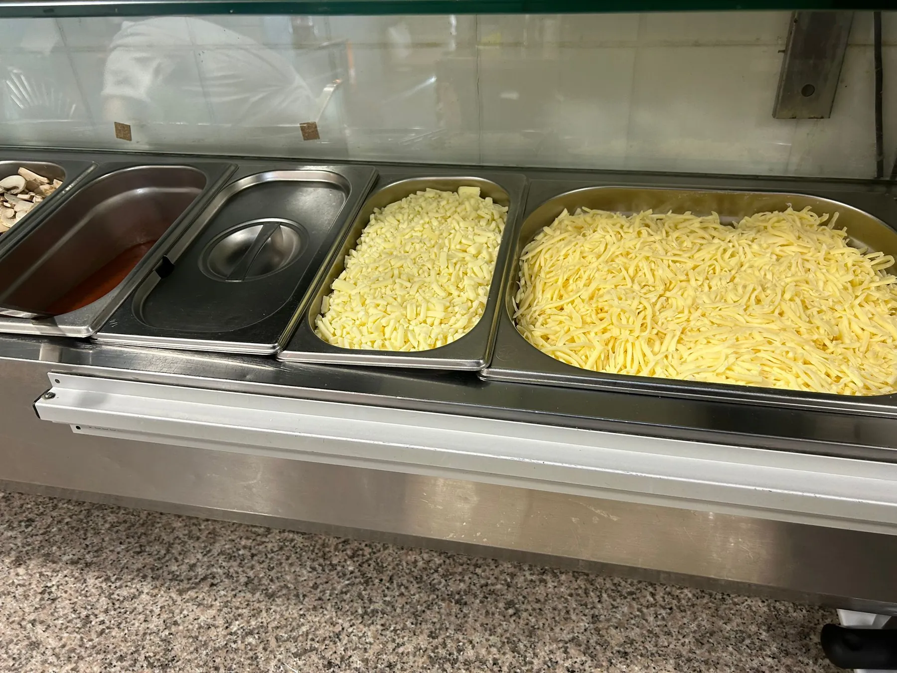 Twee bakken geraspte kaas klaar voor gebruik aan de pizzabank