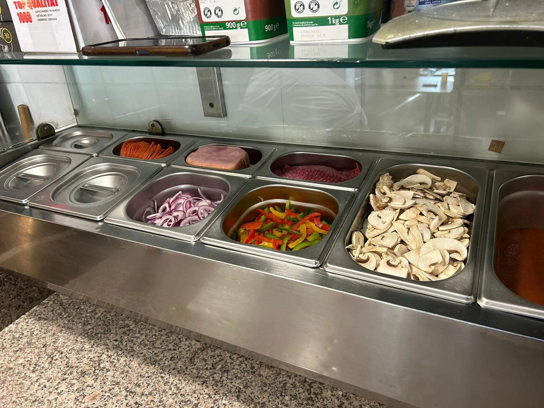 De werkbank met bakken pizzabeleg: uien, paprika, champignons en ham